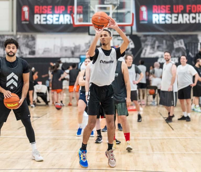 Man shooting a basketball surrounded by other players